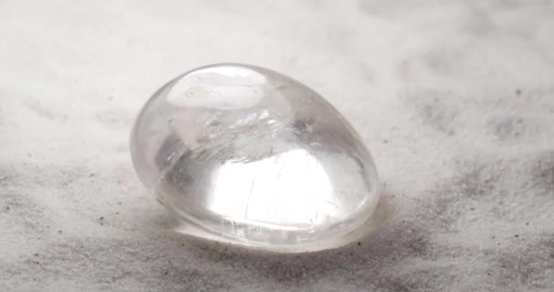 Rhinestone or rock crystal gem rotating on sand — Stock Video