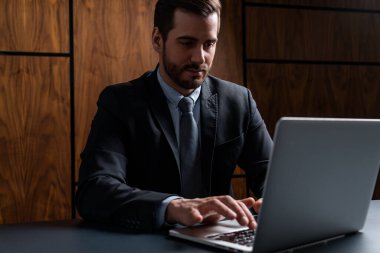 Dizüstü bilgisayarda kontratı yazan takım elbiseli yakışıklı bir adam. Yükümlülükleri almak için hukuki güce girme kavramı. Resmi giysi.