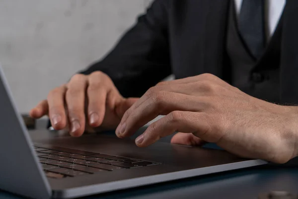 Hands of man in suit using laptop