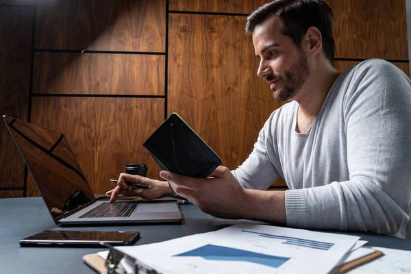 Ein gutaussehender Mann im Büro tippt den Vertrag auf dem Laptop. Das Konzept der Internet-Suche. Lässiges Tragen. — Stockfoto