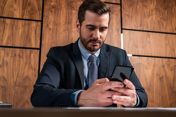 Ein Geschäftsmann im Anzug tippt auf seinem Smartphone. Formales Tragen. — Stockfoto
