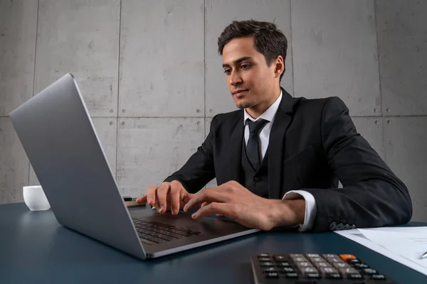 Konzentrierter junger Mann benutzt Laptop im Büro — Stockfoto