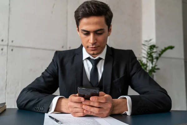 Seriöser junger Geschäftsmann schreibt SMS im Büro — Stockfoto