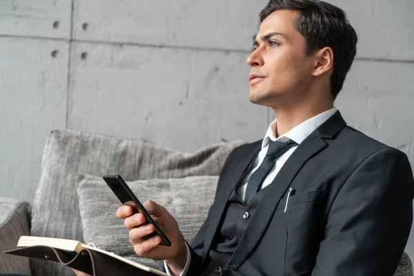 Uomo premuroso con telefono e notebook in poltrona — Foto Stock