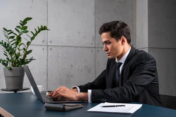 Schwerwiegender junger Mann tippt im Büro auf Laptop — Stockfoto