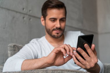 Koltukta akıllı telefon kullanan bulanık bir adam.