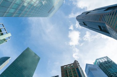 Gündüz vakti Singapur şehrinin resimli gökdelenlerinin alçak açılı görüntüsü. Finansal bölge ve Asya bölgesindeki ticaret merkezi. Başarı kavramı. Yüksek teknoloji dünyasındaki modern binalar.