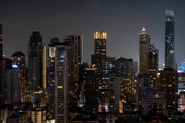 Gece vakti Bangkok siluetinin panoramik görüntüsü. Tayland 'ın aydınlatılmış şehir merkezi. Çağdaş binaların dış yüzeyi camdan..