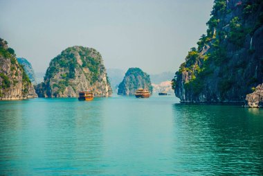 Halong Körfezi 'nin kaya adaları arasında yüzen geleneksel tekneler