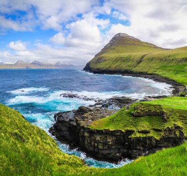 Faroe Adaları 'ndaki Gjogv' un dalgaları ve yeşil yamaçları