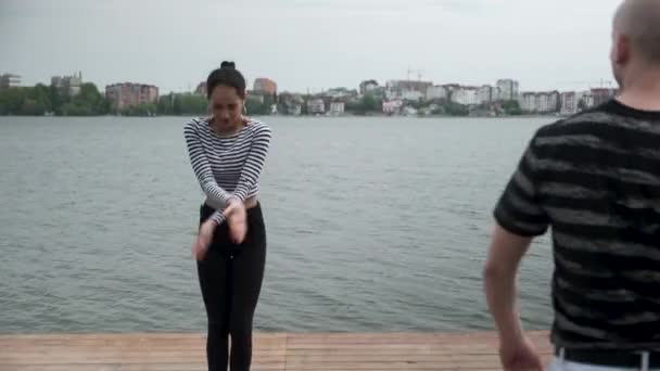 O casal apaixonado dança social bachata pier no lago, horizonte da cidade — Vídeo de Stock