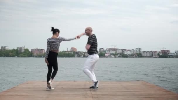 O casal apaixonado dança social bachata pier no lago vista ampla — Vídeo de Stock