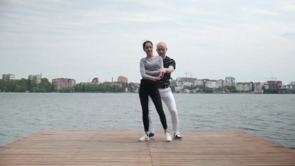 O casal apaixonado dança social bachata pier no lago vista ampla — Vídeo de Stock