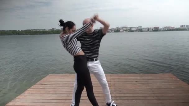 O casal apaixonado dança social bachata pier no lago, horizonte da cidade — Vídeo de Stock