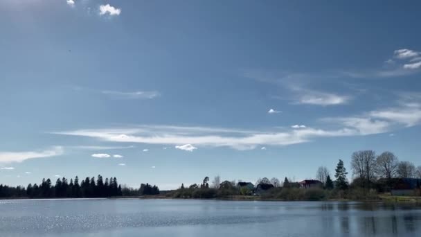 vue panoramique sur le lac. ciel bleu et nuages blancs reflétés dans l'eau. à l'horizon, vous pouvez voir la forêt et les maisons dans le village .