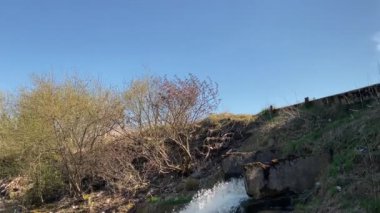 Güçlü bir su akıntısı demir bir borudan nehre dökülür. Şelale. Nehre salınımlar