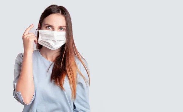 Tıbbi ameliyat maskesi takan Avrupalı bir kadın (Ukraynalı). Coronavirus Koruma, covid-19, virüs, grip, kavrayabilir. Tıbbi bir maske takıyor, çıkarıyor.