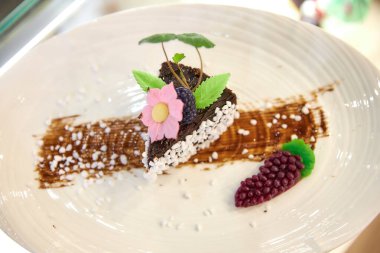 Beyaz hindistan cevizi toplarıyla süslenmiş bir parça çikolatalı pasta.