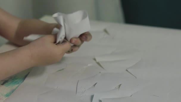 Кавказька дитина стискає білий аркуш паперу в клубок. Зблизька. 4K UHD — стокове відео