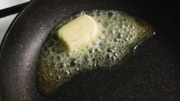 La mantequilla se fríe en una sartén oscura antiadherente. La mantequilla se derrite en una sartén caliente — Vídeos de Stock