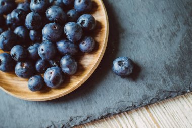 Böğürtlenler bir tabakta koyu bir arka planda