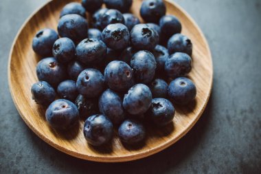 Böğürtlenler bir tabakta koyu bir arka planda