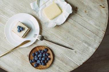 Masada beyaz bir tabağın üzerinde yaban mersinli ve tereyağlı bal keki.
