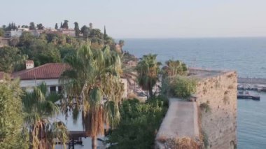 Genç kadın elleri akıllı telefondan fotoğraf çekiyor. Eski Antalya, Kaleici limanı, deniz manzarası ve sisin içindeki dağlar.