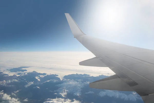 Montanhas na neve a partir da janela do avião e asa de um avião. Céu, nuvens e montanhas com vista panorâmica — Fotografia de Stock