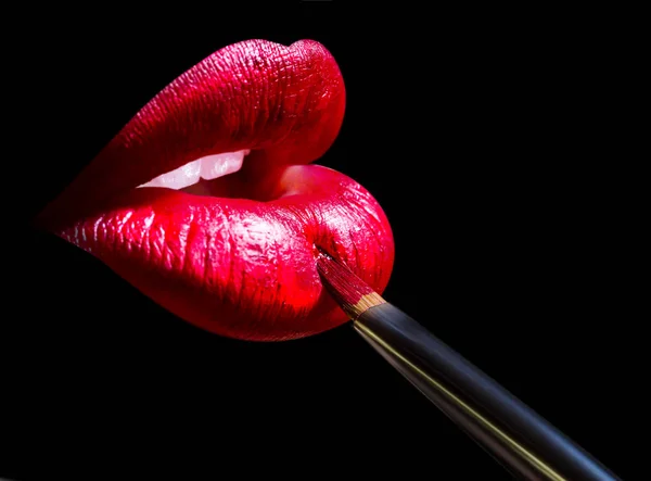 Kosmetik für Lippen auf dem Mund der Frau mit Pinsel zum Auftragen von Make-up isoliert auf schwarzem Hintergrund. Mode professionelle Kosmetik für Lippen. sexy Mund attraktive Mädchen. Nahaufnahme mit rotem Lippenstift — Stockfoto