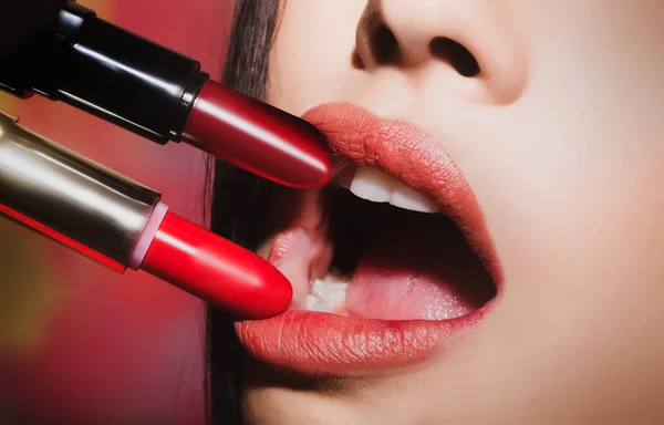 Makeup for girls. Range of lipsticks for female lips. Two lipstick near female lips close up. Red and pink lipstick, open your mouth for the sensual makeup, cosmetic palette