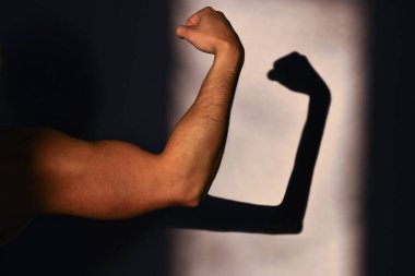 Fiziksel güç ve güçsüzlük. Sporcu ve duvardaki, ince bir gölge, yansıma güçlü el. Beklenen ve gerçeklik. Spor başarıları ve zafer