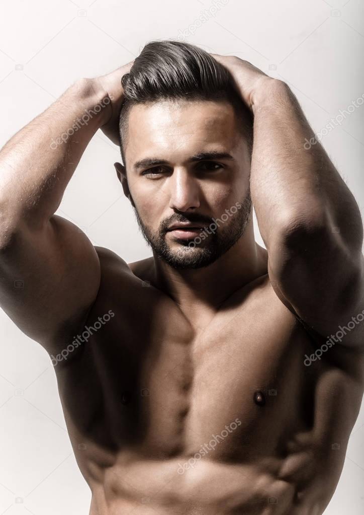 Man with naked body touches his hair. Sexy guy with bare chest and idealistic muscles. Male model, close up. Bearded young strong man closeup