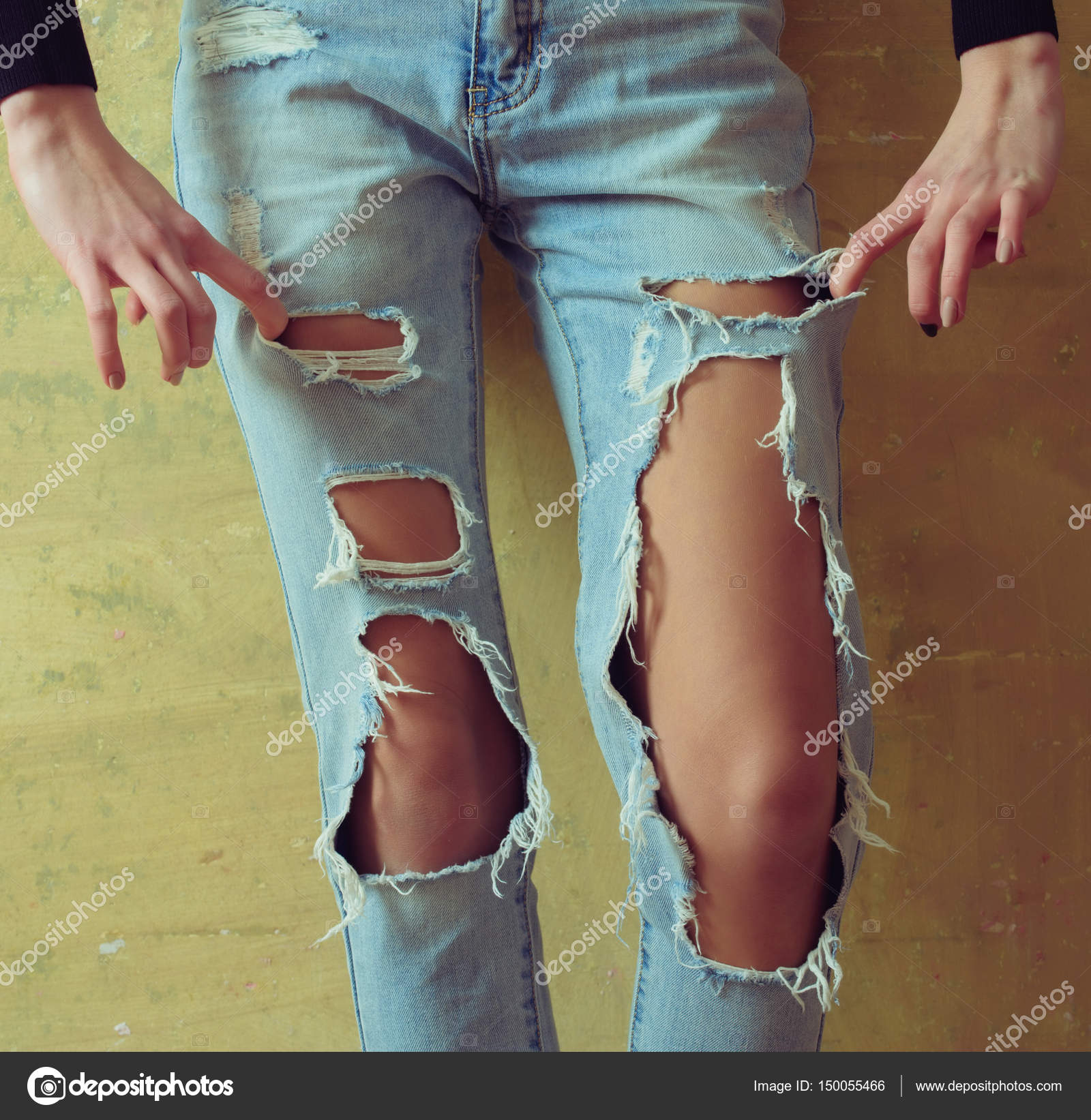 В одной руке джул. Ноги в рваных джинсах. Девушка в рваных джинсах. Девушка в порванных джинсах. Девушка в дырявых джинсах.