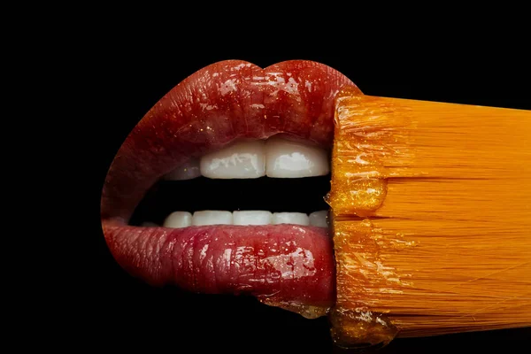 Concepto de labios cosméticos. Brillo labial aislado sobre fondo negro, boca femenina con labios y dientes rojos. Cepillo para pintalabios y brillo de cerca. Boca femenina sensual y beso. Francés besos —  Fotos de Stock