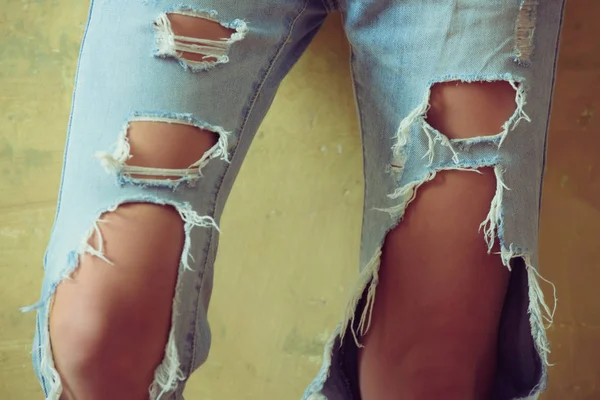 Piernas y rodillas femeninas en jeans rotos. Ropa de mezclilla de moda para niñas. Pantalones con agujeros, hipster, moda callejera. Ropa para el verano. La temporada es primavera-verano —  Fotos de Stock