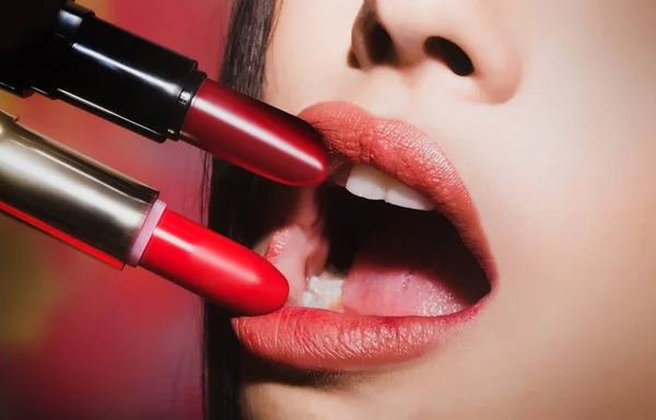 Maquillaje para chicas. Gama de lápices labiales para labios femeninos. Dos pintalabios cerca de los labios femeninos se cierran. Lápiz labial rojo y rosa, abra la boca para el maquillaje sensual, paleta de cosméticos — Foto de Stock