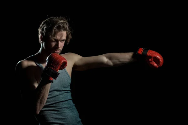 Boxing man, blow, hit. Portrait of attractive kickboxer in the dark. Young man boxing, exercise in the gym. Boxer in red gloves and gray shirt — Stock Photo, Image