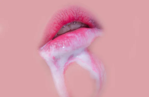 Pink lips with white cream or secretions from the genitals. Sexy female mouth with braces on teeth. Sweet dessert at the mouth of young sexy girl. Natural lips closeup on solid body background