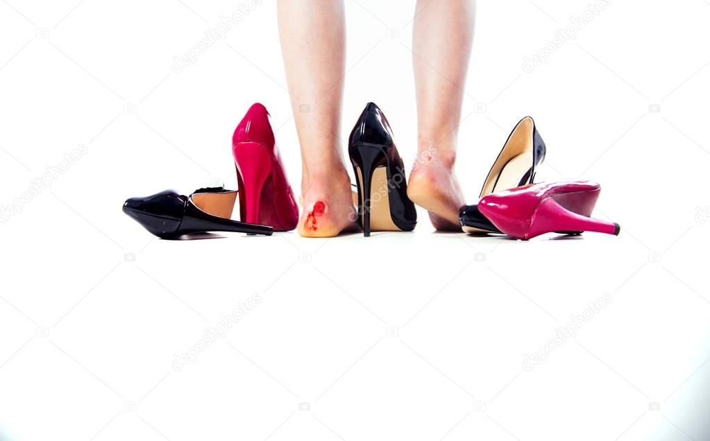 Woman with injured foot. Foot pain. Body health problem, blisters, wounds on skin. Painful barefoot woman with high heels in the white background. Girl have ankle joint ache of high-heeled shoe