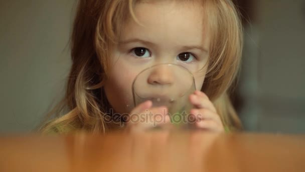 Dziecko pije mleko od szkła przy stole. Użyteczne napój dla dziecka. Mleka i przetworów mlecznych produktów na śniadanie lub kolację, żywności dla niemowląt. Cute baby z długie, białe włosy w kuchni w domu. Zdrowie, zdrowe jedzenie — Wideo stockowe