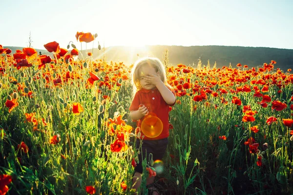 Sun nature eyes, boy on the field with poppies closes his eyes from sun's rays, strong light at noon, solstice, protection of eyes from the sun. Beautiful child on the field outside the city on walk — Stock Photo, Image