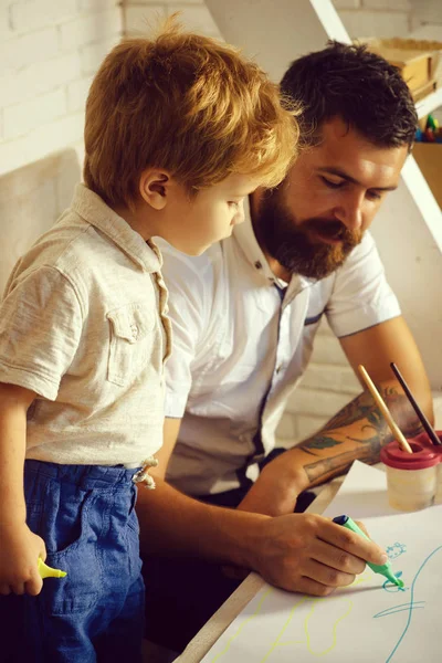 Team work drawing, father and son paint together, father teaches his son how to paint correct and beautiful on paper. Family creativity and education at home, father artist and son attentive student