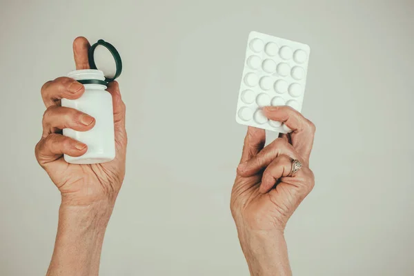 Pills medications, hands. Old female hands hold pills in Blister Pack and pill bottle, packaging for drugs: painkillers, antibiotics, vitamins. Medicine, health care, close up mature woman hold pill