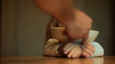 Komik çocuk yemek mutfakta oynuyor. Çocuk yemek istemiyor. Bebek maması ve iştahsızlık. Neşeli oyun plaka mutfak tablosundaki ile. Yürümeye başlayan çocuk yakışıklı uzun saç kahvaltı baba ile Kahvaltı