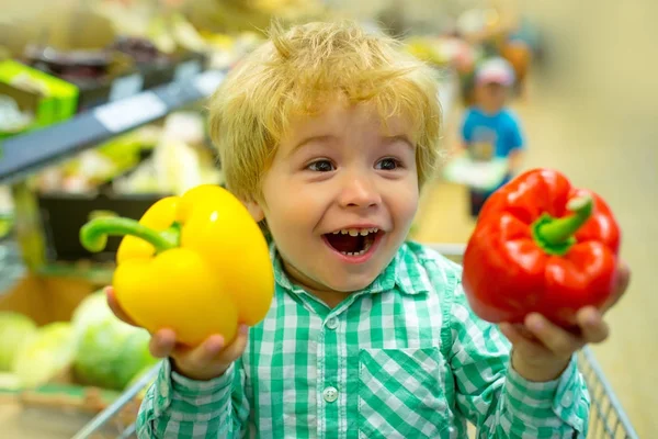 Happy vegetables child. Cute kid in supermarket holds bulgarian sweet pepper for salad. Healthy food, fresh vegetables for lunch. Shopping in store, fresh products for kitchen and cooking. Baby food — Stock Photo, Image