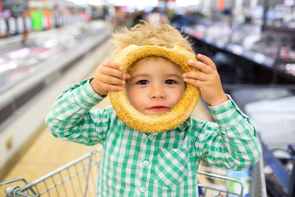 Refeição infantil feliz. Para cartaz infantil. História de comida engraçada. Grande escolha de comida. Garoto engraçado bonito no supermercado brincando com pão rollaway. Lanche no menu infantil. Engraçado garoto retrato sem glúten — Fotografia de Stock