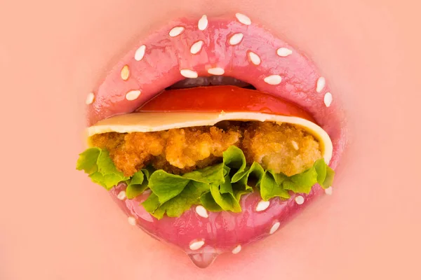 Вкусный сэндвич. Сэндвич во рту. Женские губы с кунжутом. Помидоры, зелень, сыр и коллаж в женских губах. Соблазнение еды. Милые розовые губы. Круг рта — стоковое фото