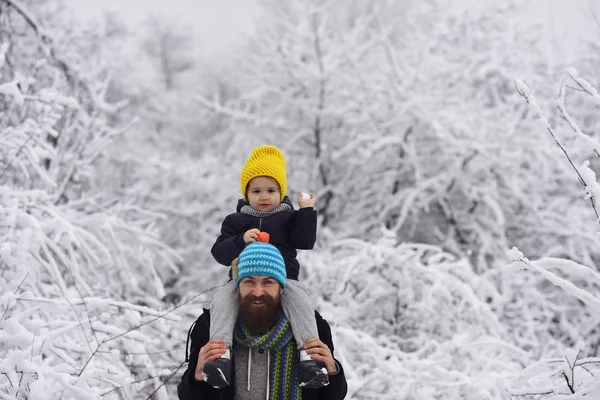 Παιχνίδι χιονοστιβάδας. Παίζοντας χιονόμπαλες, ευτυχισμένο παιδί παίζει με το χιόνι και γενειοφόρος χαρούμενος ο πατέρας. Φιλία στην παιδική ηλικία, υποστήριξη του πατέρα του. Αγόρι με άνδρα με τα πόδια μέσα από ένα χιονισμένο πάρκο χειμώνα — Φωτογραφία Αρχείου