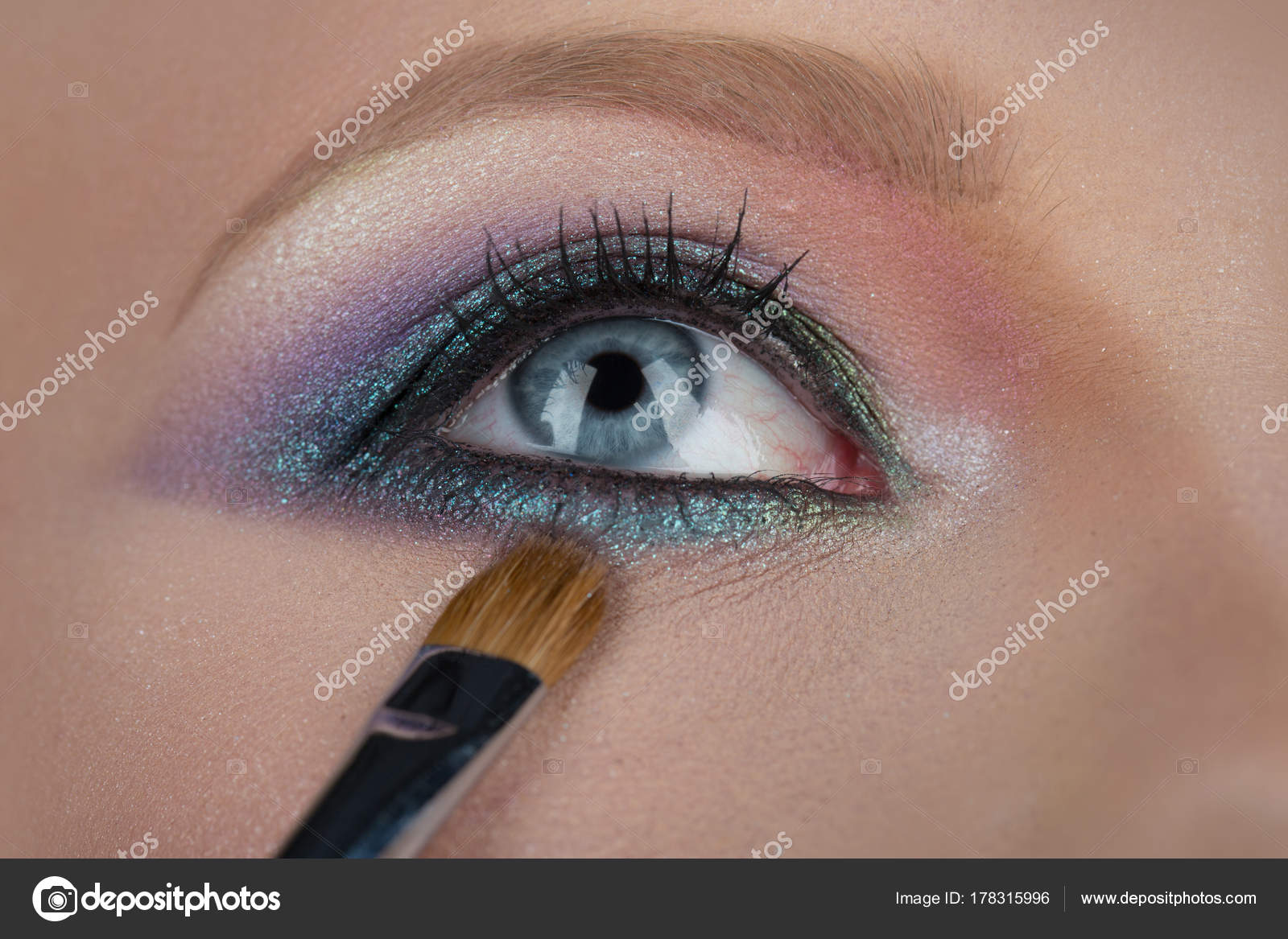Trucco per gli occhi. Close,up occhi azzurri femminili. Belli cosmetici per il viso, donna seducente sguardo. Pennello per ombretti blu e rosa.